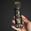 Guerrier Totem Aztèque en obsidienne dorée tenu en main, une sculpture en pierre naturelle idéale pour la décoration et symbole de protection.