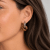 Boucles d’oreilles donut en œil de tigre portées à l’oreille